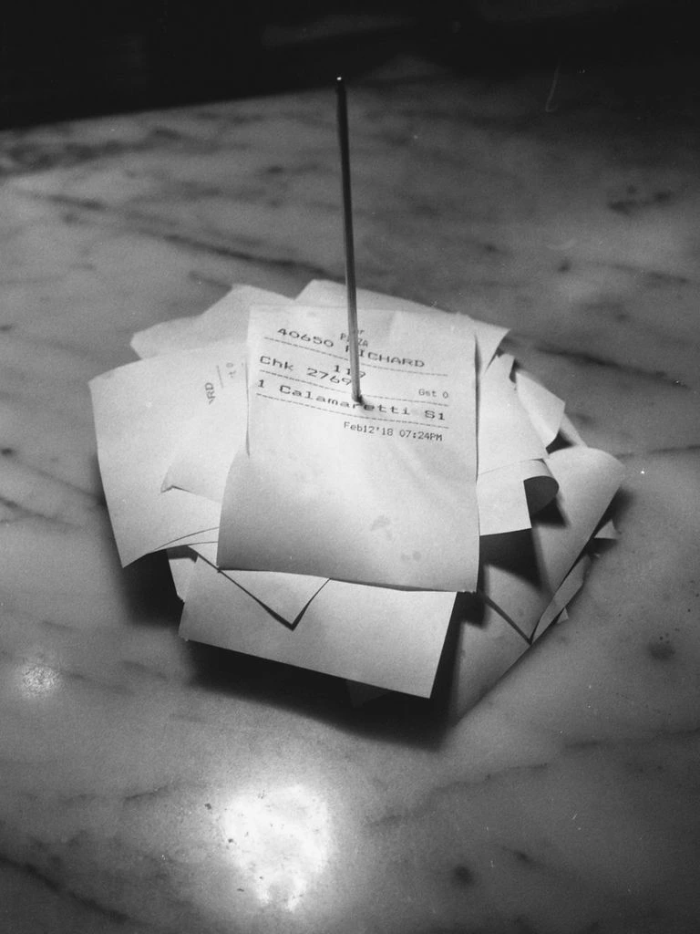A printed receipt and a shipping carrier scan slip sit on a desk — the two records the Receipt-Match engine cross-checks for every submission.